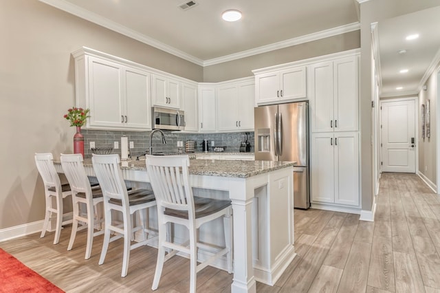 kitchen featuring white cabinetry, light stone counters, stainless steel appliances, and decorative backsplash