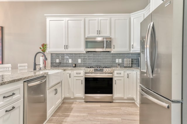 kitchen featuring light stone countertops, decorative backsplash, stainless steel appliances, and white cabinets