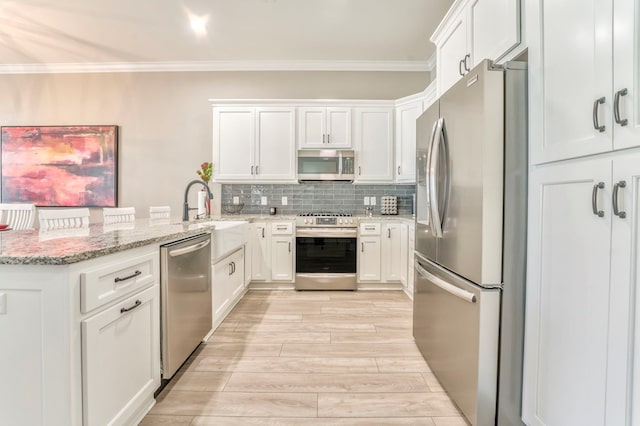 kitchen featuring light stone counters, sink, stainless steel appliances, and white cabinets