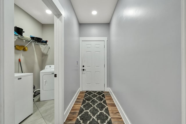 laundry room with washing machine and clothes dryer and light hardwood / wood-style flooring