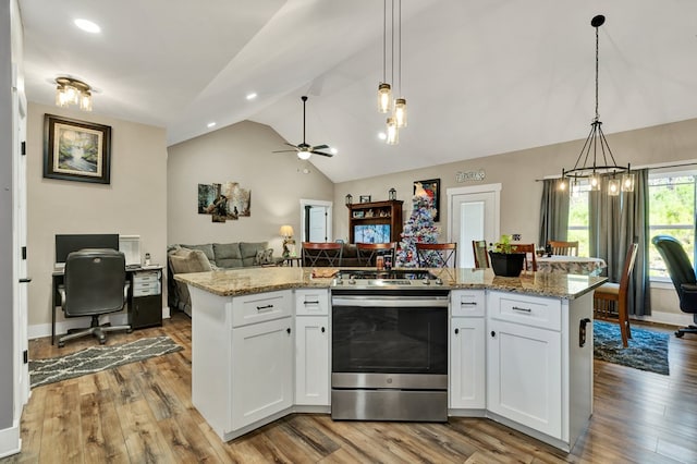 kitchen with pendant lighting, stainless steel range oven, a center island with sink, and white cabinets