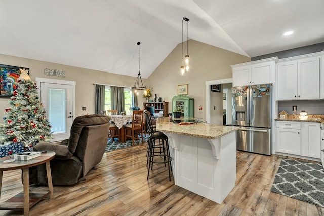 kitchen featuring pendant lighting, a breakfast bar, white cabinetry, a kitchen island, and stainless steel fridge with ice dispenser