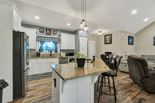 kitchen featuring pendant lighting, stainless steel appliances, a kitchen island, and white cabinets