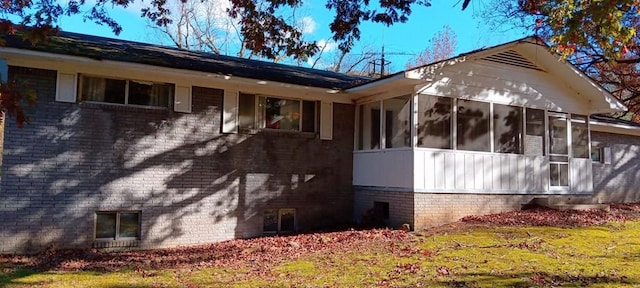 view of property exterior featuring a sunroom and a lawn