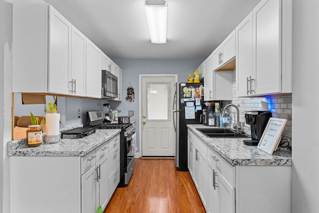 1369 Lida St, Dalton, GA 30721 - kitchen featuring stainless steel appliances, light wood-style flooring, decorative backsplash, and white cabinets