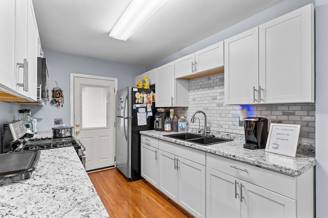 1369 Lida St, Dalton, GA 30721 - kitchen featuring appliances with stainless steel finishes, white cabinets, light wood-style floors, decorative backsplash, and light stone countertops