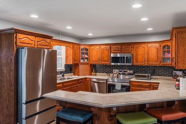 2163 Red Leaf Ln, Soddy Daisy, TN 37379 - kitchen featuring stainless steel appliances, brown cabinetry, a peninsula, glass insert cabinets, and recessed lighting