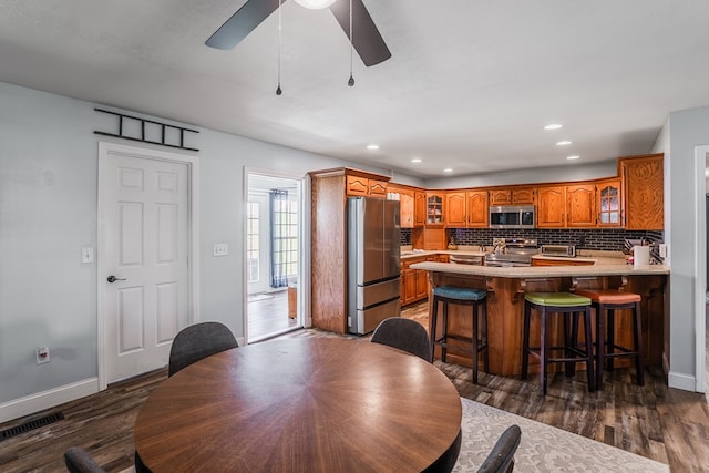 2163 Red Leaf Ln, Soddy Daisy, TN 37379 - kitchen with stainless steel appliances, brown cabinets, a peninsula, glass insert cabinets, and recessed lighting