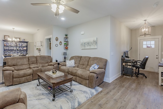 living room with ceiling fan with notable chandelier and light wood-type flooring