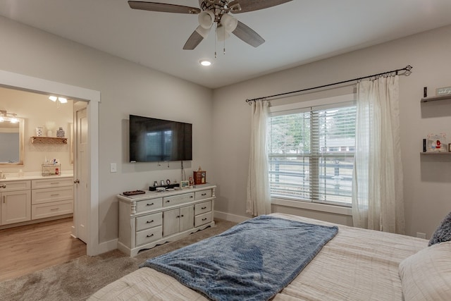 bedroom featuring ceiling fan, connected bathroom, and light colored carpet