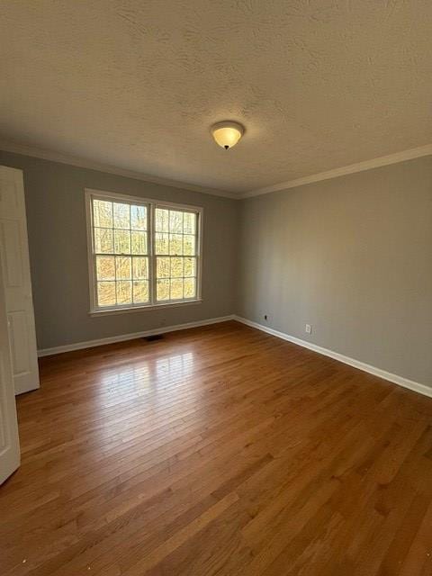 empty room with hardwood / wood-style flooring, crown molding, and a textured ceiling