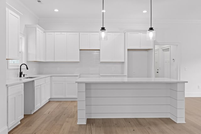 kitchen with sink, decorative light fixtures, white cabinets, and a kitchen island