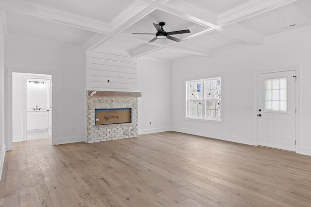 unfurnished living room featuring light hardwood / wood-style flooring, a fireplace, coffered ceiling, and beamed ceiling