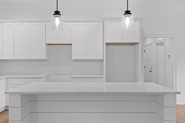 kitchen with pendant lighting, a kitchen island, light hardwood / wood-style flooring, and white cabinets