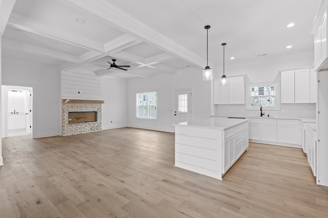 kitchen featuring white cabinetry, a fireplace, a kitchen island, and pendant lighting