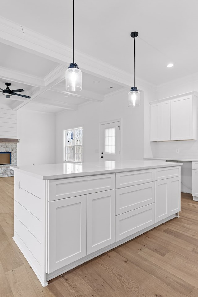 details featuring hardwood / wood-style flooring, crown molding, ceiling fan, beam ceiling, and a stone fireplace