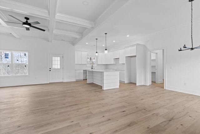 unfurnished living room with ceiling fan with notable chandelier, coffered ceiling, crown molding, beam ceiling, and light hardwood / wood-style flooring