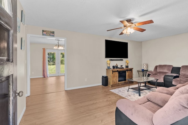 living room featuring ceiling fan, light hardwood / wood-style floors, and a textured ceiling