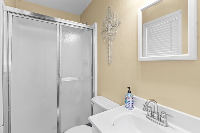 bathroom featuring a shower with door, vanity, and toilet