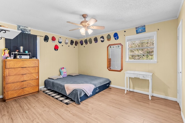 bedroom featuring ceiling fan, wood-type flooring, and a textured ceiling