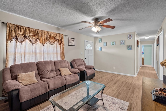 living room with ceiling fan, a textured ceiling, and light wood-type flooring