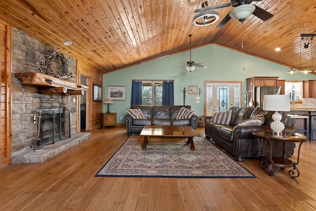 living room featuring ceiling fan, a stone fireplace, wood finished floors, and wood ceiling