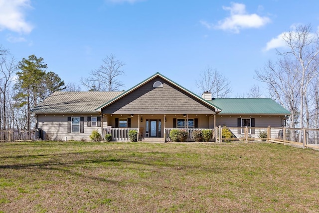 view of front facade featuring a chimney, a front lawn, a porch, and fence