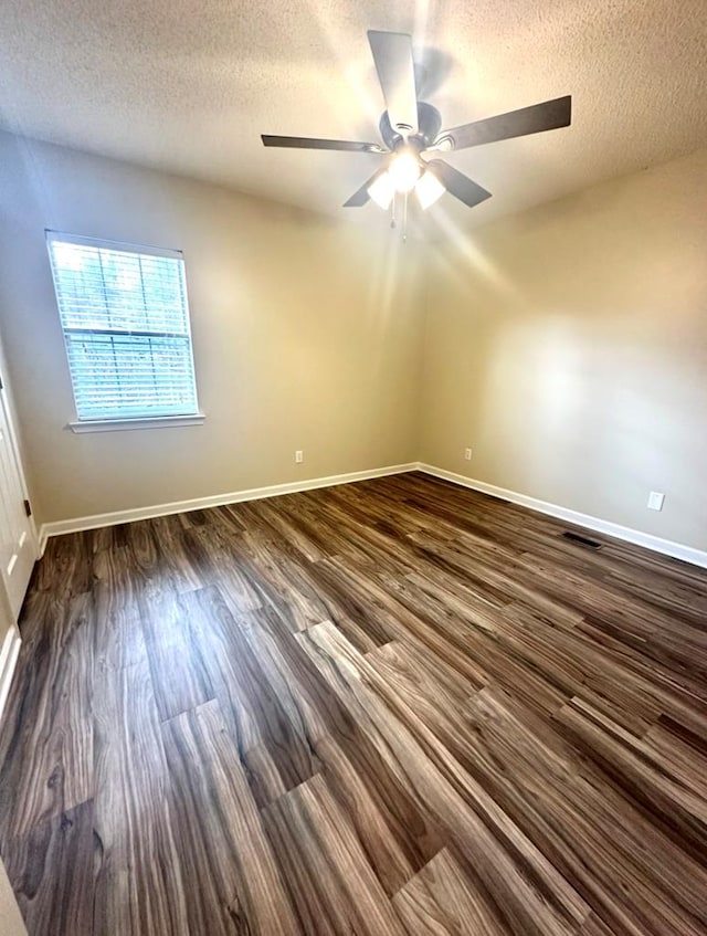 spare room with dark wood-type flooring, ceiling fan, and a textured ceiling