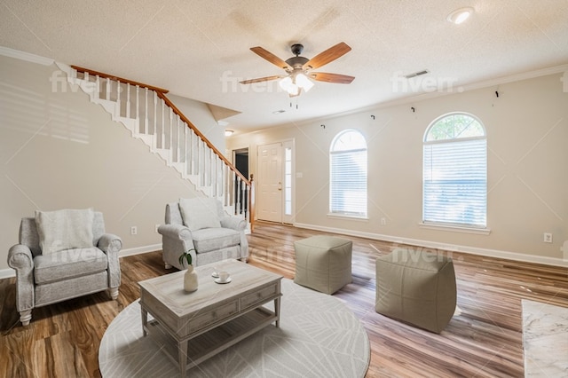 living room with wood-type flooring, crown molding, ceiling fan, and a textured ceiling