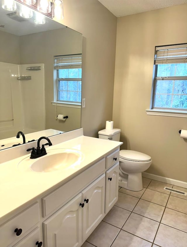 bathroom featuring vanity, toilet, tile patterned flooring, and a wealth of natural light