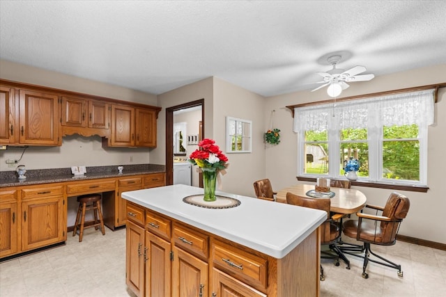 3932 Tibbs Bridge Rd, Dalton, GA 30721 - kitchen with brown cabinetry, ceiling fan, a kitchen island, built in study area, and a textured ceiling