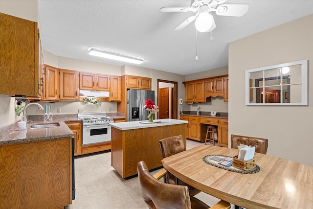 3932 Tibbs Bridge Rd, Dalton, GA 30721 - kitchen with stainless steel refrigerator with ice dispenser, high end white range, a kitchen island, under cabinet range hood, and ceiling fan