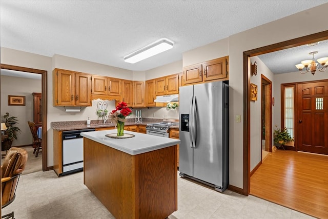 3932 Tibbs Bridge Rd, Dalton, GA 30721 - kitchen with appliances with stainless steel finishes, a chandelier, under cabinet range hood, a center island, and a textured ceiling