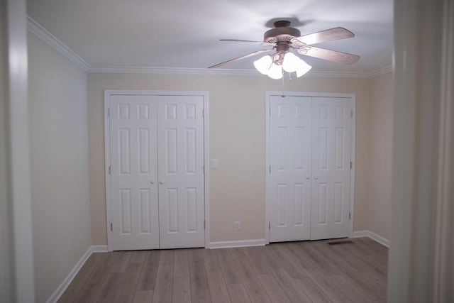 unfurnished bedroom with multiple closets, ceiling fan, ornamental molding, and light hardwood / wood-style floors