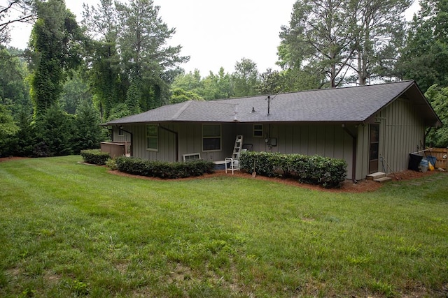 rear view of property featuring a hot tub and a lawn