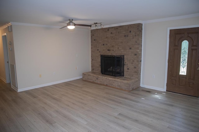 unfurnished living room featuring crown molding, ceiling fan, a brick fireplace, and light wood-type flooring