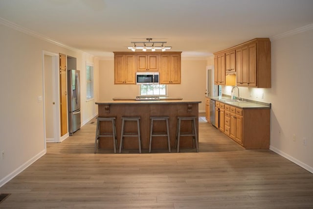 kitchen with ornamental molding, stainless steel appliances, and sink