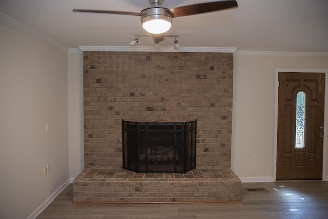 unfurnished living room featuring a brick fireplace, crown molding, wood-type flooring, and ceiling fan