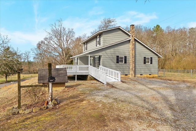 view of side of home featuring crawl space, a wooden deck, a chimney, and fence