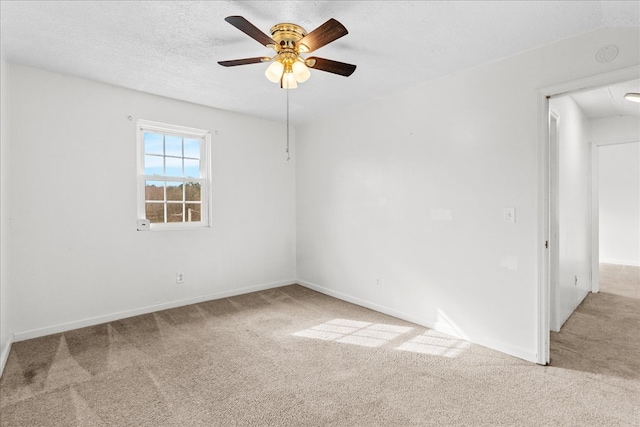 carpeted spare room with a ceiling fan, baseboards, and a textured ceiling