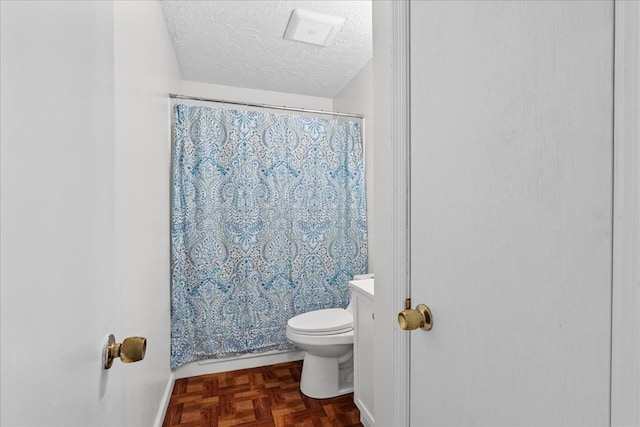 bathroom featuring a shower with curtain, toilet, and a textured ceiling