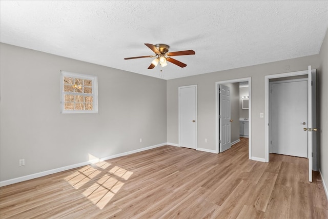 unfurnished bedroom featuring light wood-style flooring, a textured ceiling, baseboards, and a ceiling fan