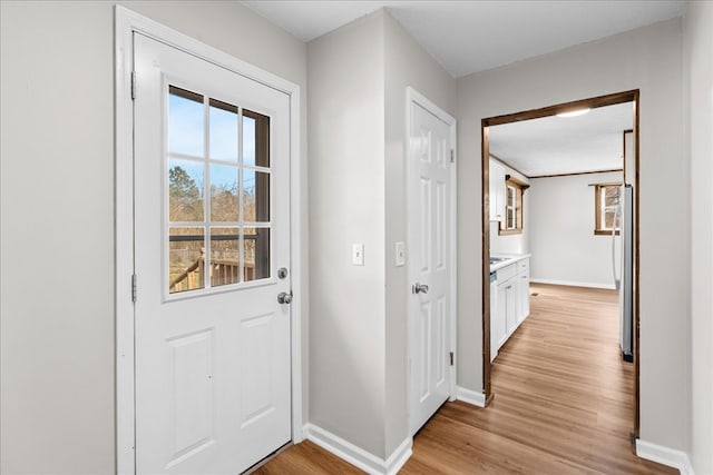 doorway to outside featuring light wood-type flooring and baseboards