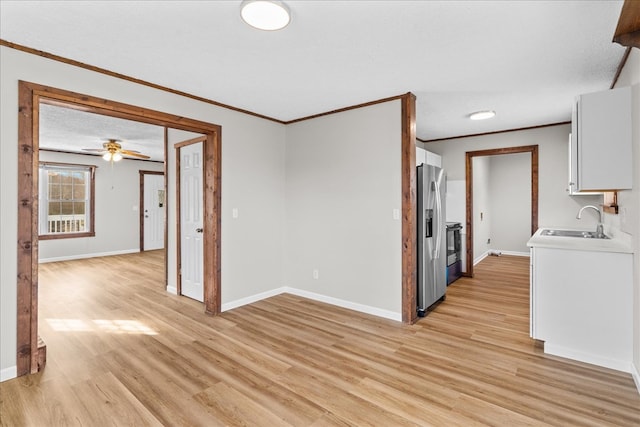 interior space featuring light wood-style flooring, baseboards, stainless steel refrigerator with ice dispenser, and a sink