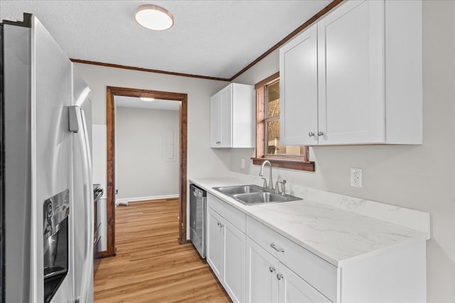 kitchen featuring light countertops, appliances with stainless steel finishes, light wood-style floors, white cabinets, and a sink