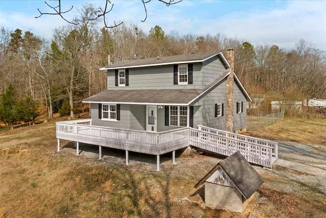 back of property featuring a deck, fence, and a chimney