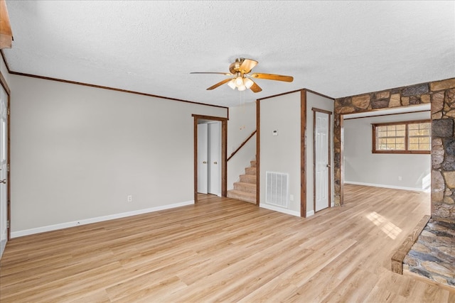 unfurnished living room featuring visible vents, a textured ceiling, light wood-style flooring, and ornamental molding