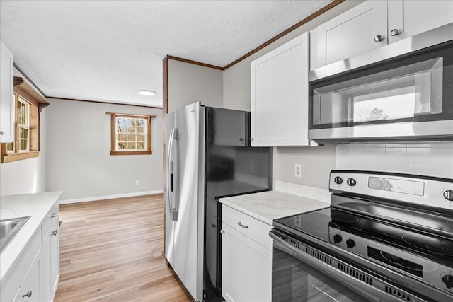 kitchen featuring a textured ceiling, stainless steel appliances, white cabinets, crown molding, and light wood finished floors