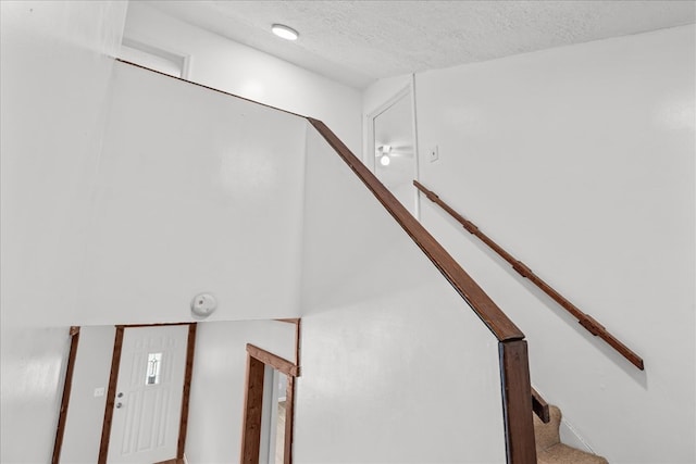 stairs featuring a textured ceiling