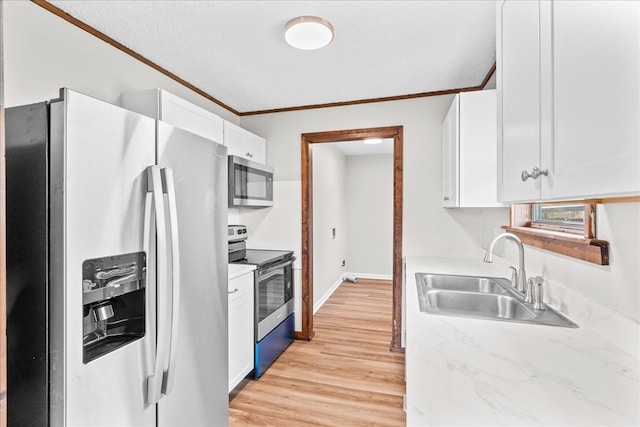 kitchen featuring light wood-style flooring, a sink, appliances with stainless steel finishes, white cabinets, and crown molding